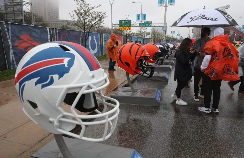 Fans try to stay dry as they check out the oversized team helmets at the NFL Draft Experience on Thursday April 29, 2021.

Draft 7
