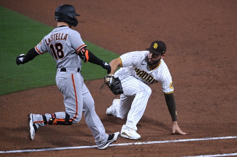 Apr 30, 2021; San Diego, California, USA; San Francisco Giants second baseman Tommy La Stella (18) is tagged out by San Diego Padres first baseman Eric Hosmer (R) after grounding out during the fifth inning at Petco Park. Mandatory Credit: Orlando Ramirez-USA TODAY Sports