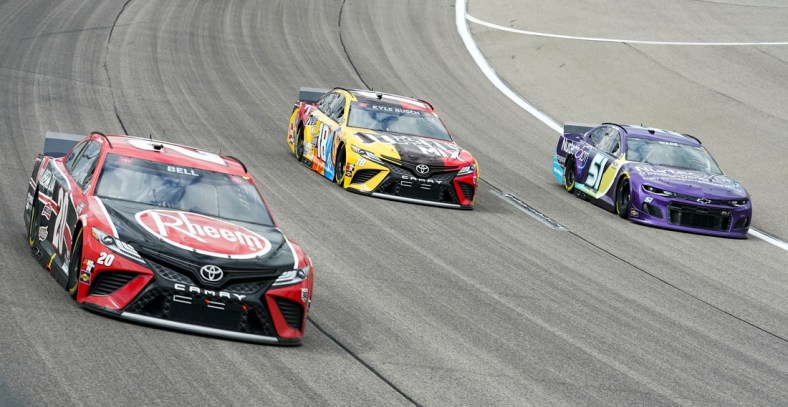 May 2, 2021; Kansas City, Kansas, USA; NASCAR Cup Series driver Kyle Busch (18) races against driver Christopher Bell (20) and driver Cody Ware (51) during the Buschy McBusch Race 400 at Kansas Speedway. Mandatory Credit: Jay Biggerstaff-USA TODAY Sports