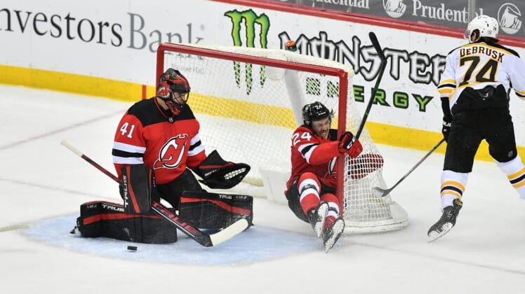 May 3, 2021; Newark, New Jersey, USA; New Jersey Devils defenseman Ty Smith (24) slides into the goal while defending a shot against Boston Bruins left wing Jake DeBrusk (74) during the first period at Prudential Center. Mandatory Credit: Catalina Fragoso-USA TODAY Sports
