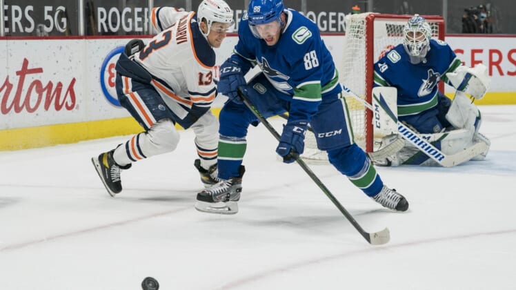 May 3, 2021; Vancouver, British Columbia, CAN; Edmonton Oilers forward Jesse Puljujarvi (13) defends Vancouver Canucks defenseman Nate Schmidt (88) in the first period at Rogers Arena. Mandatory Credit: Bob Frid-USA TODAY Sports