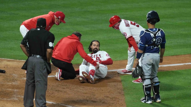 May 3, 2021; Anaheim, California, USA;  Los Angeles Angels third baseman Anthony Rendon (6) is attended by an athletic trainer after suffering an injury in the eighth inning as manager Joe Maddon (left) and third base coach Brian Buttterfield watch against the Tampa Bay Rays at Angel Stadium. Mandatory Credit: Kirby Lee-USA TODAY Sports