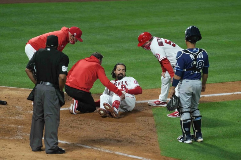 May 3, 2021; Anaheim, California, USA;  Los Angeles Angels third baseman Anthony Rendon (6) is attended by an athletic trainer after suffering an injury in the eighth inning as manager Joe Maddon (left) and third base coach Brian Buttterfield watch against the Tampa Bay Rays at Angel Stadium. Mandatory Credit: Kirby Lee-USA TODAY Sports
