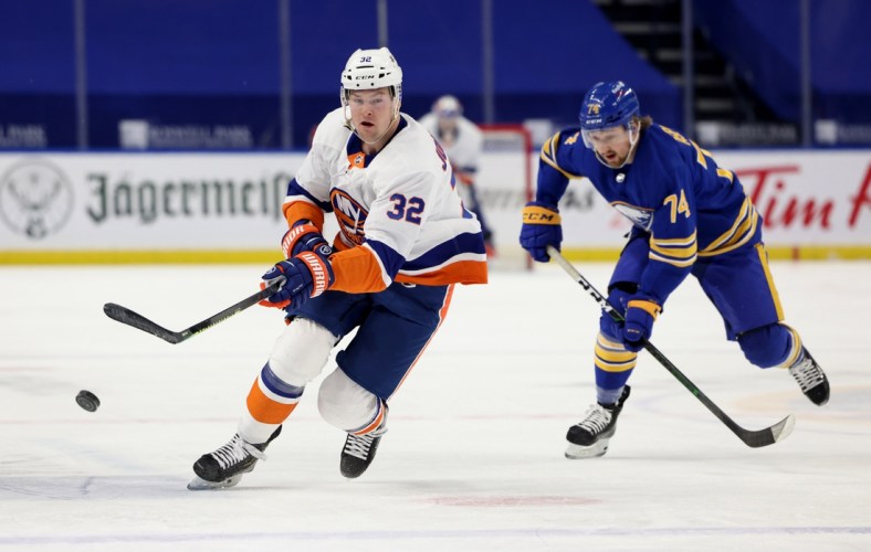 May 4, 2021; Buffalo, New York, USA;  New York Islanders left wing Ross Johnston (32) shoots the puck up ice as Buffalo Sabres center Rasmus Asplund (74) tries to defend during the first period at KeyBank Center. Mandatory Credit: Timothy T. Ludwig-USA TODAY Sports