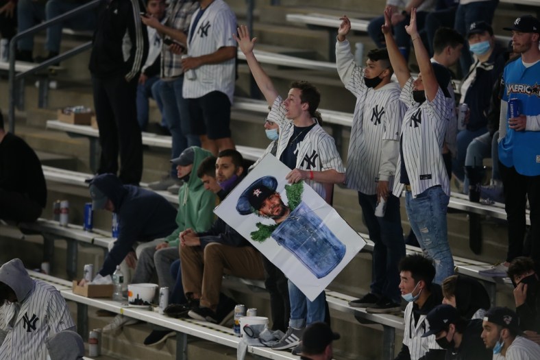 May 4, 2021; Bronx, New York, USA; A New York Yankees fan holding a picture of Houston Astros second baseman Jose Altuve (27) in a trash can reacts during the fifth inning at Yankee Stadium. Mandatory Credit: Brad Penner-USA TODAY Sports