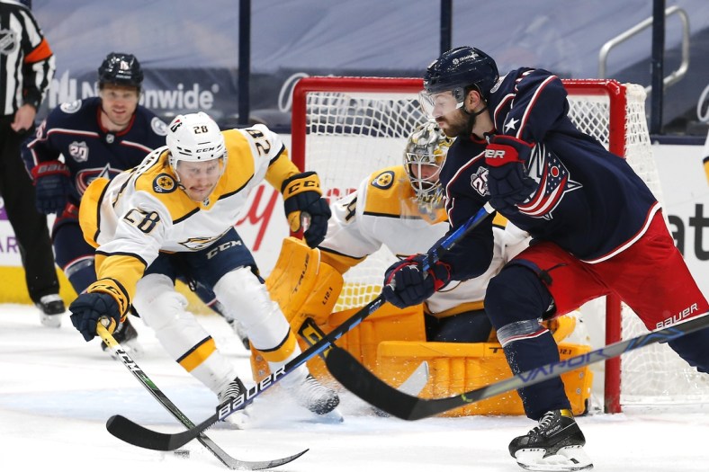 May 5, 2021; Columbus, Ohio, USA; Columbus Blue Jackets right wing Oliver Bjorkstrand (28) passes the puck as Nashville Predators right wing Eeli Tolvanen (28) reaches for the steal during the first period at Nationwide Arena. Mandatory Credit: Russell LaBounty-USA TODAY Sports