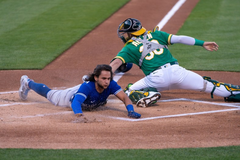May 5, 2021; Oakland, California, USA; Toronto Blue Jays shortstop Bo Bichette (11) reaches home against Oakland Athletics catcher Austin Allen (30) during the first inning at RingCentral Coliseum. Mandatory Credit: Neville E. Guard-USA TODAY Sports