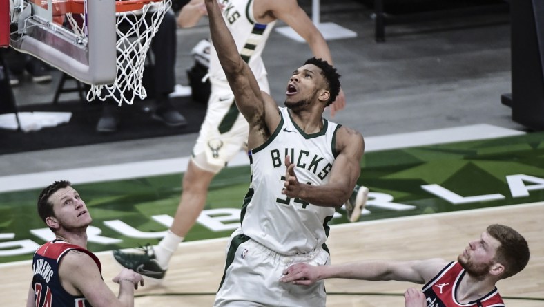 May 5, 2021; Milwaukee, Wisconsin, USA; Milwaukee Bucks forward Giannis Antetokounmpo (34) scores a basket against Washington Wizards guard Garrison Mathews (24) and forward Davis Bertans (42) in the fourth quarter at Fiserv Forum. Mandatory Credit: Benny Sieu-USA TODAY Sports