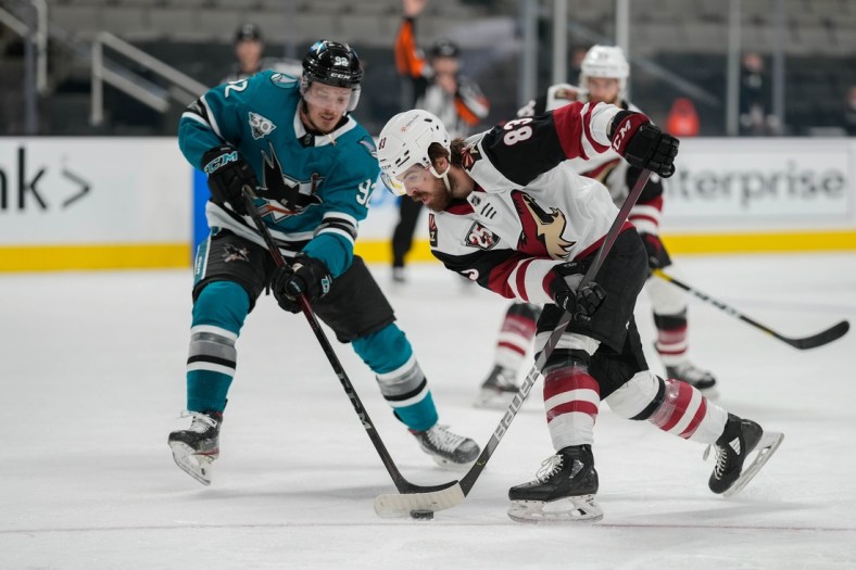 May 7, 2021; San Jose, California, USA; Arizona Coyotes right wing Conor Garland (83) and San Jose Sharks left wing Rudolfs Balcers (92) battle for control of the puck during the second period at SAP Center at San Jose. Mandatory Credit: Stan Szeto-USA TODAY Sports