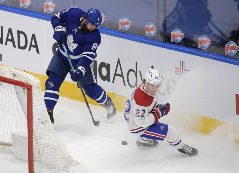 May 8, 2021; Toronto, Ontario, CAN; Toronto Maple Leafs defenseman Jake Muzzin (8) shoots the puck past Montreal Canadiens forward Cole Caulfield (22) in the first period at Scotiabank Arena. Mandatory Credit: Dan Hamilton-USA TODAY Sports