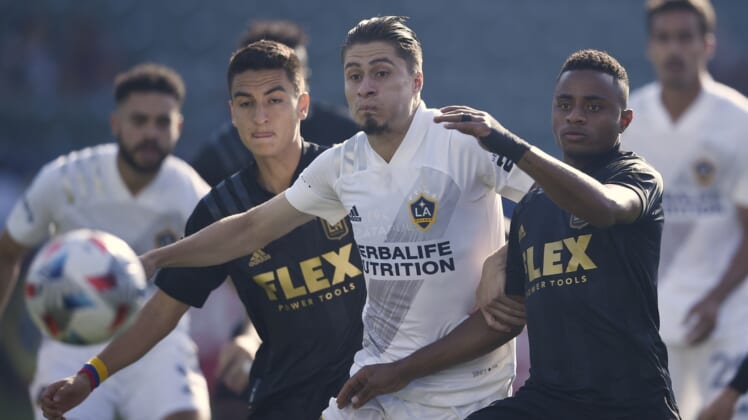 May 8, 2021; Carson, California, USA; LA Galaxy defender Jorge Villafa  a (19) and Los Angeles FC defender Diego Palacios (12) battle for the ball during the first half at Dignity Health Sports Park. Mandatory Credit: Kelvin Kuo-USA TODAY Sports