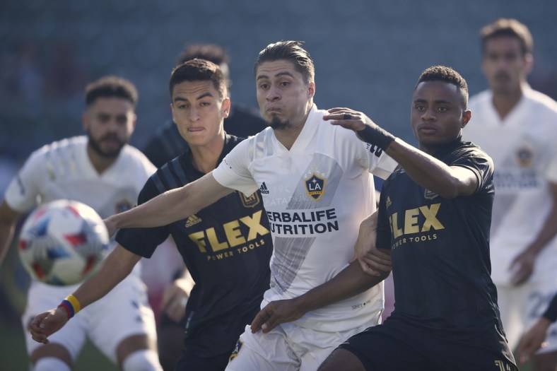 May 8, 2021; Carson, California, USA; LA Galaxy defender Jorge Villafa  a (19) and Los Angeles FC defender Diego Palacios (12) battle for the ball during the first half at Dignity Health Sports Park. Mandatory Credit: Kelvin Kuo-USA TODAY Sports