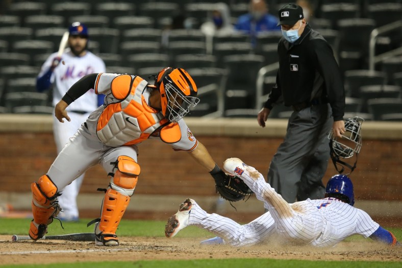 May 11, 2021; New York City, New York, USA; New York Mets third baseman Jonathan Villar (R) scores a run ahead of the tag of Baltimore Orioles catcher Pedro Severino (L) on a hit by Mets pinch hitter Patrick Mazeika (not pictured) during the ninth inning at Citi Field. Mandatory Credit: Brad Penner-USA TODAY Sports