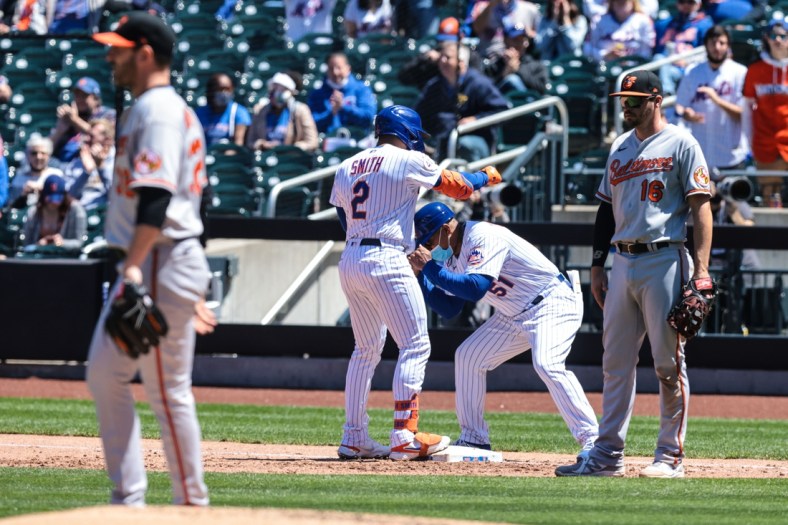 May 12, 2021; New York City, New York, USA; New York Mets first baseman Dominic Smith (2) reacts with first base coach Tony Tarasco (51) after hitting an RBI single against Baltimore Orioles starting pitcher Matt Harvey (32) during the fifth inning at Citi Field. Mandatory Credit: Vincent Carchietta-USA TODAY Sports