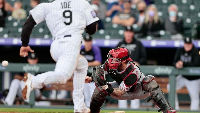 May 13, 2021; Denver, Colorado, USA; Cincinnati Reds catcher Tucker Barnhart (16) fields a throw as Colorado Rockies first baseman Connor Joe (9) runs towards home plate during the first inning at Coors Field. Mandatory Credit: Isaiah J. Downing-USA TODAY Sports