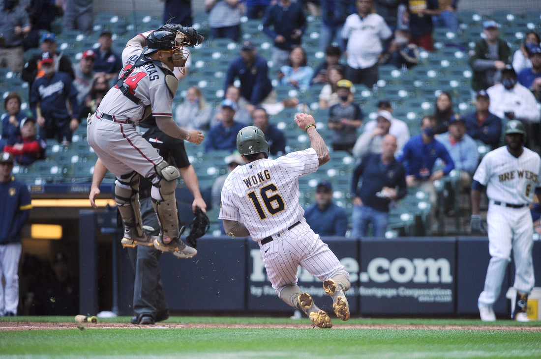 May 16, 2021; Milwaukee, Wisconsin, USA;  Milwaukee Brewers second baseman Kolten Wong (16) scores a run as the throw is high and no tag was made by Atlanta Braves catcher William Contreras (24) in the fourth inning at American Family Field. Mandatory Credit: Michael McLoone-USA TODAY Sports