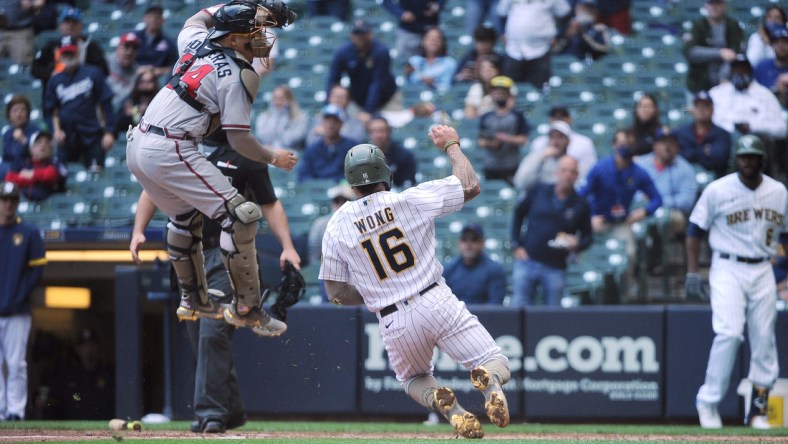 May 16, 2021; Milwaukee, Wisconsin, USA;  Milwaukee Brewers second baseman Kolten Wong (16) scores a run as the throw is high and no tag was made by Atlanta Braves catcher William Contreras (24) in the fourth inning at American Family Field. Mandatory Credit: Michael McLoone-USA TODAY Sports