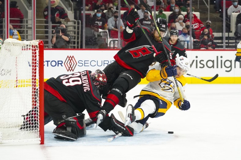 May 17, 2021; Raleigh, North Carolina, USA; Carolina Hurricanes goaltender Alex Nedeljkovic (39) and defenseman Jani Hakanpaa (58) battle Nashville Predators right wing Viktor Arvidsson (33) for the puck during the first period  in game one of the first round of the 2021 Stanley Cup Playoffs at PNC Arena. Mandatory Credit: James Guillory-USA TODAY Sports