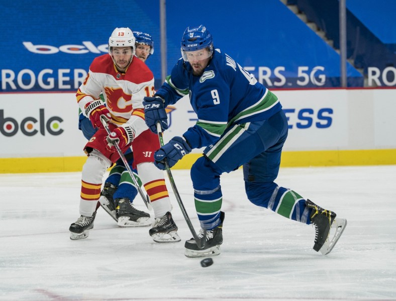 May 18, 2021; Vancouver, British Columbia, CAN; Calgary Flames forward Johnny Gaudreau (13) checks Vancouver Canucks forward J.T. Miller (9) in the second period at Rogers Arena. Mandatory Credit: Bob Frid-USA TODAY Sports