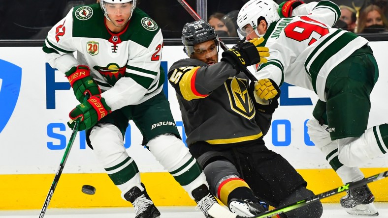 May 18, 2021; Las Vegas, Nevada, USA; Vegas Golden Knights right wing Keegan Kolesar (55) is hit by Minnesota Wild center Marcus Johansson (90) as Minnesota Wild left wing Kevin Fiala (22) chips the puck away during the second period of game two of the first round of the 2021 Stanley Cup Playoffs at T-Mobile Arena. Mandatory Credit: Stephen R. Sylvanie-USA TODAY Sports