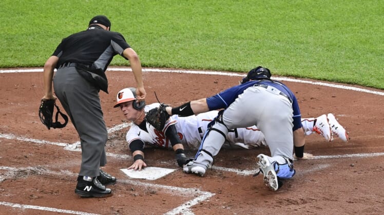 May 19, 2021; Baltimore, Maryland, USA;  Home plate umpire Vic Carapazza (19) signals Tampa Bay Rays catcher Mike Zunino (10) tags out Baltimore Orioles third baseman Ryan Mountcastle (6) at the plate during the second inning at Oriole Park at Camden Yards. Mandatory Credit: Tommy Gilligan-USA TODAY Sports