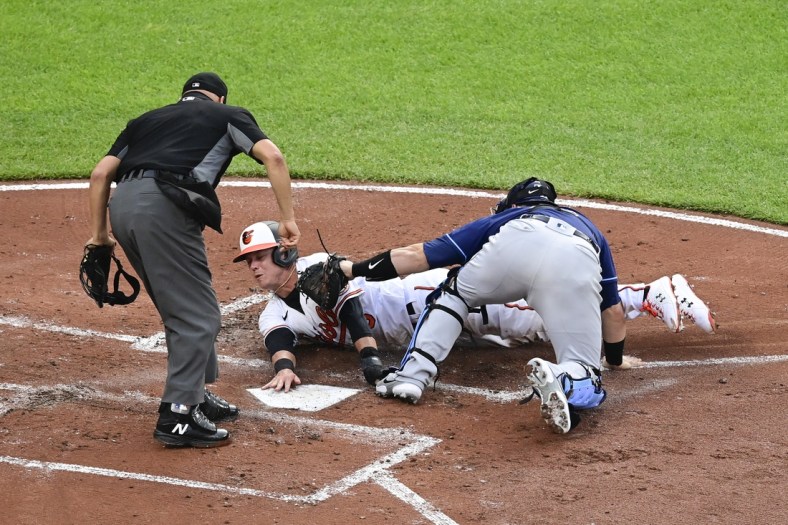May 19, 2021; Baltimore, Maryland, USA;  Home plate umpire Vic Carapazza (19) signals Tampa Bay Rays catcher Mike Zunino (10) tags out Baltimore Orioles third baseman Ryan Mountcastle (6) at the plate during the second inning at Oriole Park at Camden Yards. Mandatory Credit: Tommy Gilligan-USA TODAY Sports