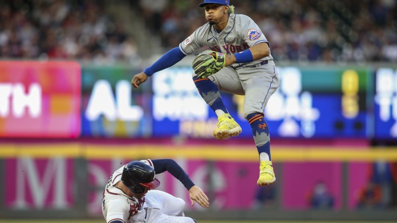 May 19, 2021; Atlanta, Georgia, USA; New York Mets shortstop Francisco Lindor (12) turns a double play over Atlanta Braves first baseman Freddie Freeman (5) in the fourth inning at Truist Park. Mandatory Credit: Brett Davis-USA TODAY Sports