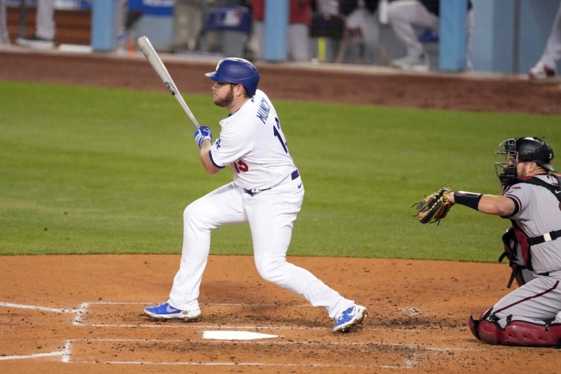 May 20, 2021; Los Angeles, California, USA; Los Angeles Dodgers second baseman Max Muncy (13) follows through on a single during the third inning as Arizona Diamondbacks catcher Stephen Vogt (21) watches  at Dodger Stadium. Mandatory Credit: Kirby Lee-USA TODAY Sports