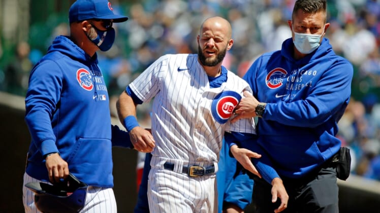 May 29, 2021; Chicago, Illinois, USA; Chicago Cubs manager David Ross (left) and trainer P.J. Mainville (right) help third baseman David Bote (13) off the field after an apparent injury as he slid into second base against the Cincinnati Reds during the fourth inning at Wrigley Field. Mandatory Credit: Jon Durr-USA TODAY Sports