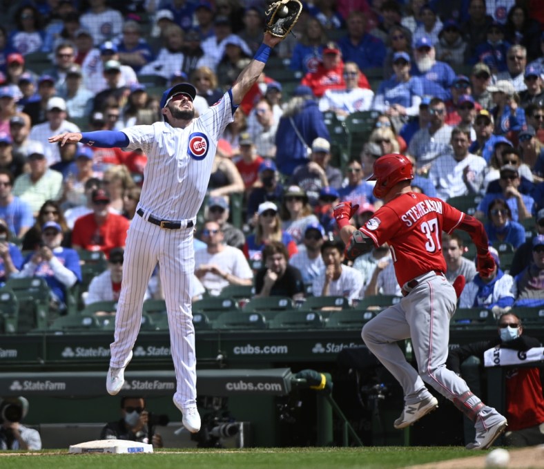 May 30, 2021; Chicago, Illinois, USA; Chicago Cubs first baseman Kris Bryant (17) leaps for the ball as Cincinnati Reds catcher Tyler Stephenson (37) is safe at first base during the fourth inning at Wrigley Field. Mandatory Credit: Matt Marton-USA TODAY Sports