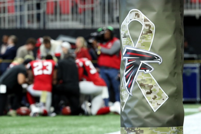 Nov 24, 2019; Atlanta, GA, USA; The Atlanta Falcons logo is shown with a camouflage ribbon on a goalpost as the Atlanta Falcons running backs pray together before their game against the Tampa Bay Buccaneers at Mercedes-Benz Stadium. Mandatory Credit: Jason Getz-USA TODAY Sports