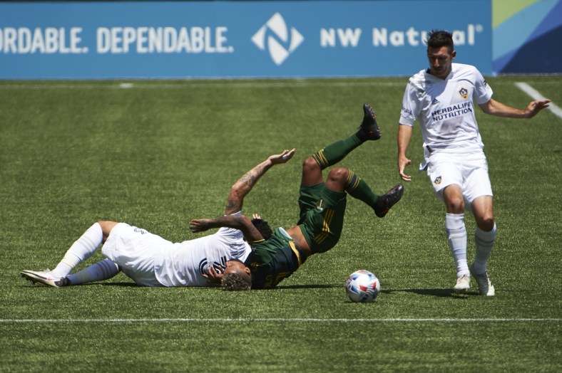 May 22, 2021; Portland, Oregon, USA; Los Angeles Galaxy defender Derrick Williams (3) slides into Portland Timbers forward Andy Polo (7) during the first half at Providence Park. Williams was issued a red card on the play. Mandatory Credit: Troy Wayrynen-USA TODAY Sports