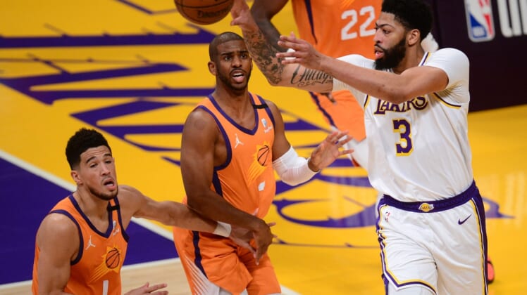 May 30, 2021; Los Angeles, California, USA; Los Angeles Lakers forward Anthony Davis (3) passes the ball against Phoenix Suns guard Chris Paul (3) and guard Devin Booker (1) during the first half in game four of the first round of the 2021 NBA Playoffs. at Staples Center. Mandatory Credit: Gary A. Vasquez-USA TODAY Sports