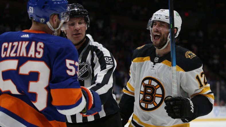 Jun 3, 2021; Uniondale, New York, USA; Boston Bruins right wing Craig Smith (12) yells at New York Islanders center Casey Cizikas (53) as the two are separated by linesman Mark Shewchyk (92) during the second period of game three of the second round of the 2021 Stanley Cup Playoffs at Nassau Veterans Memorial Coliseum. Mandatory Credit: Brad Penner-USA TODAY Sports