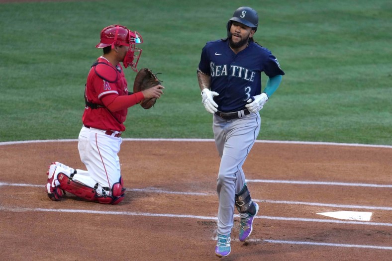 Jun 4, 2021; Anaheim, California, USA; Seattle Mariners shortstop J.P. Crawford (3) crosses home plate after hitting a solo home run in the first inning as Los Angeles Angels catcher Kurt Suzuki (24) watches at Angel Stadium. Mandatory Credit: Kirby Lee-USA TODAY Sports