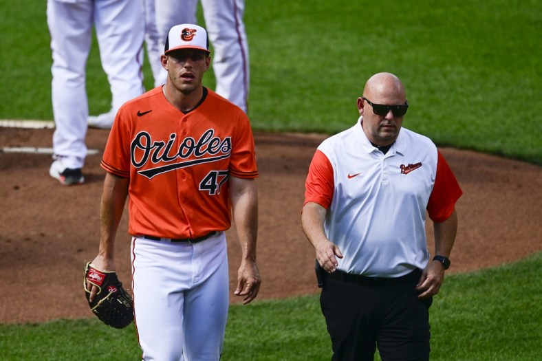 Jun 5, 2021; Baltimore, Maryland, USA;  Baltimore Orioles starting pitcher John Means (47) leaves the game with a trainer during the first inning against the Cleveland Indians at Oriole Park at Camden Yards. Mandatory Credit: Tommy Gilligan-USA TODAY Sports