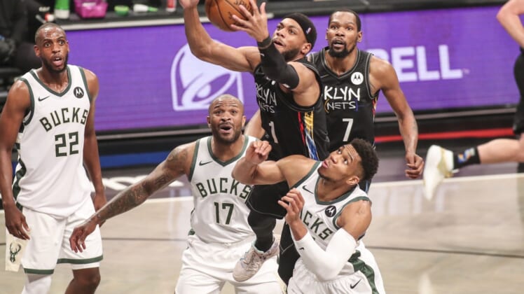 Jun 7, 2021; Brooklyn, New York, USA; Brooklyn Nets guard Bruce Brown (1) jumps over Milwaukee Bucks forwards P.J. Tucker (17) and Giannis Antetokounmpo (34) to grab a rebound in the third quarter during game two in the second round of the 2021 NBA Playoffs. at Barclays Center. Mandatory Credit: Wendell Cruz-USA TODAY Sports