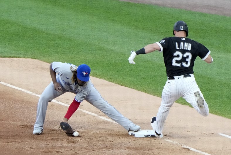 Jun 9, 2021; Chicago, Illinois, USA; Toronto Blue Jays designated hitter Vladimir Guerrero Jr. (27) drops the ball making Chicago White Sox third baseman Jake Lamb (23) safe at first on an error during the first inning at Guaranteed Rate Field. Mandatory Credit: Mike Dinovo-USA TODAY Sports