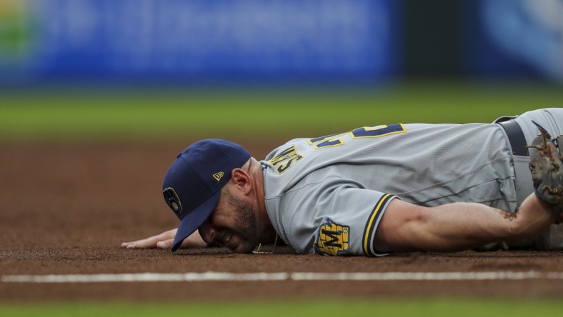 Jun 9, 2021; Cincinnati, Ohio, USA; Milwaukee Brewers third baseman Travis Shaw (21) falls and is injured after attempting to catch a ground ball against the Cincinnati Reds in the second inning at Great American Ball Park. Mandatory Credit: Katie Stratman-USA TODAY Sports