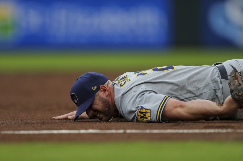 Jun 9, 2021; Cincinnati, Ohio, USA; Milwaukee Brewers third baseman Travis Shaw (21) falls and is injured after attempting to catch a ground ball against the Cincinnati Reds in the second inning at Great American Ball Park. Mandatory Credit: Katie Stratman-USA TODAY Sports