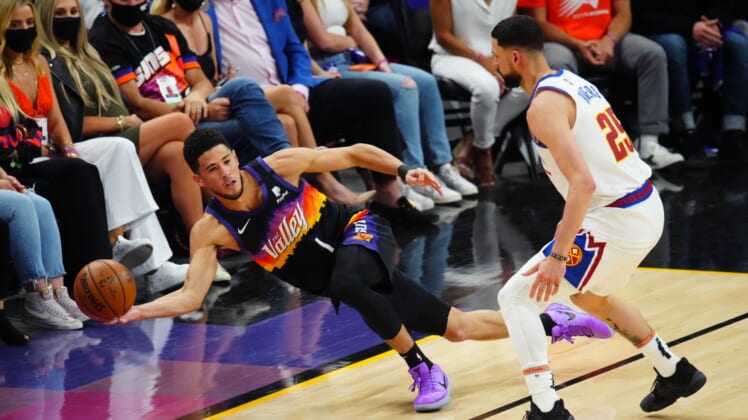 Jun 9, 2021; Phoenix, Arizona, USA; Phoenix Suns guard Devin Booker (1) passes the ball as he dives to save it from going out of bounds against Denver Nuggets guard Austin Rivers in the first half during game two in the second round of the 2021 NBA Playoffs at Phoenix Suns Arena. Mandatory Credit: Mark J. Rebilas-USA TODAY Sports