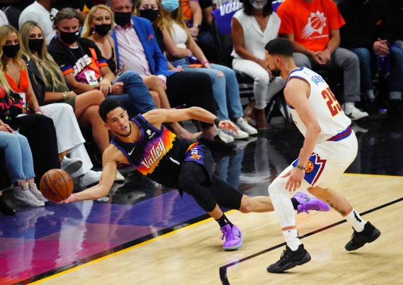 Jun 9, 2021; Phoenix, Arizona, USA; Phoenix Suns guard Devin Booker (1) passes the ball as he dives to save it from going out of bounds against Denver Nuggets guard Austin Rivers in the first half during game two in the second round of the 2021 NBA Playoffs at Phoenix Suns Arena. Mandatory Credit: Mark J. Rebilas-USA TODAY Sports