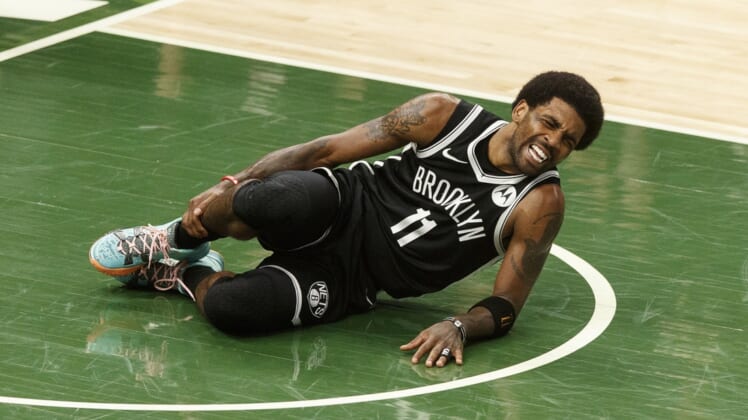 Jun 13, 2021; Milwaukee, Wisconsin, USA;  Brooklyn Nets guard Kyrie Irving (11) grabs his leg after being injured during the second quarter against the Milwaukee Bucks during game four in the second round of the 2021 NBA Playoffs. at Fiserv Forum. Mandatory Credit: Jeff Hanisch-USA TODAY Sports