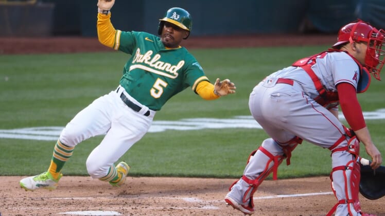 Jun 14, 2021; Oakland, California, USA; Oakland Athletics left fielder Tony Kemp (5) slides safely home behind Los Angeles Angels catcher Max Stassi (33) during the third inning at RingCentral Coliseum. Mandatory Credit: Kelley L Cox-USA TODAY Sports