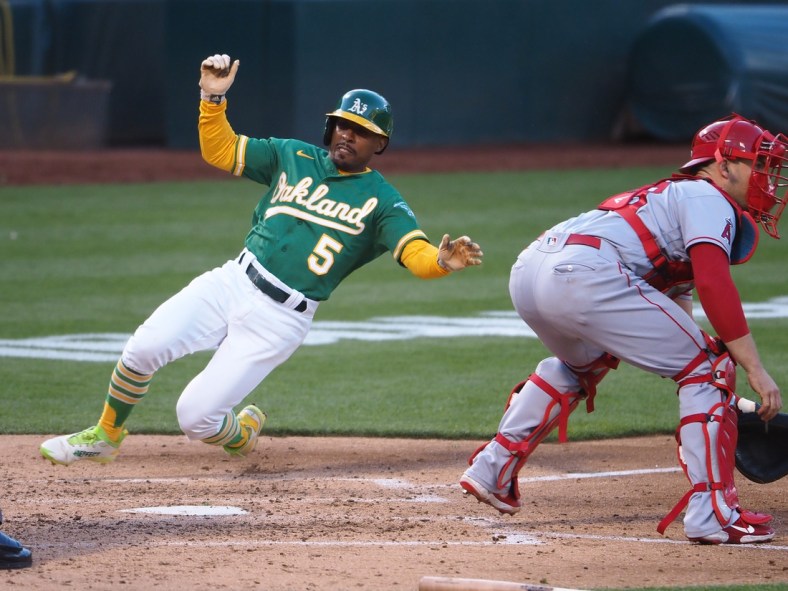 Jun 14, 2021; Oakland, California, USA; Oakland Athletics left fielder Tony Kemp (5) slides safely home behind Los Angeles Angels catcher Max Stassi (33) during the third inning at RingCentral Coliseum. Mandatory Credit: Kelley L Cox-USA TODAY Sports