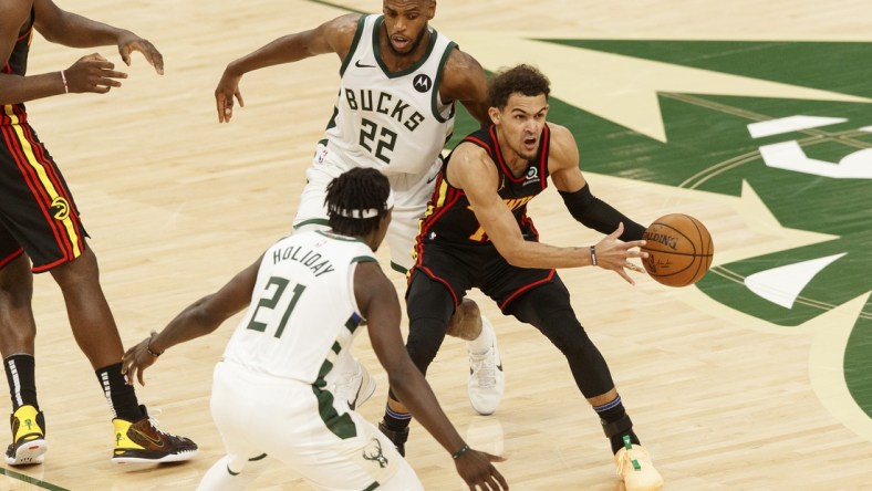 Jun 25, 2021; Milwaukee, Wisconsin, USA; Atlanta Hawks guard Trae Young (11) looks to pass the ball while defended by Milwaukee Bucks forward Khris Middleton (22) and guard Jrue Holiday (21) during the third quarter during game two of the Eastern Conference Finals for the 2021 NBA Playoffs at Fiserv Forum. Mandatory Credit: Jeff Hanisch-USA TODAY Sports