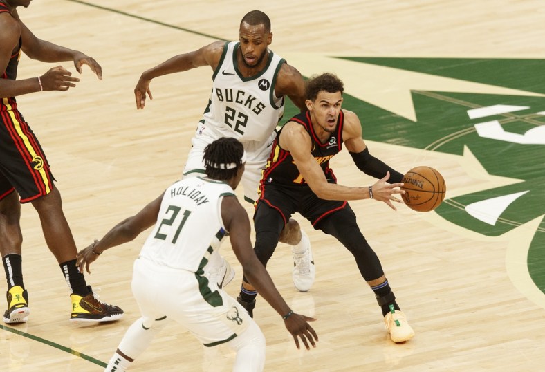 Jun 25, 2021; Milwaukee, Wisconsin, USA; Atlanta Hawks guard Trae Young (11) looks to pass the ball while defended by Milwaukee Bucks forward Khris Middleton (22) and guard Jrue Holiday (21) during the third quarter during game two of the Eastern Conference Finals for the 2021 NBA Playoffs at Fiserv Forum. Mandatory Credit: Jeff Hanisch-USA TODAY Sports