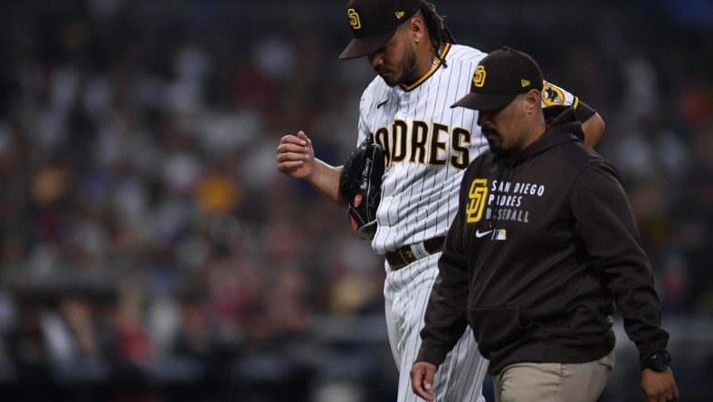 Jun 26, 2021; San Diego, California, USA; San Diego Padres starting pitcher Dinelson Lamet (left) walks to the dugout accompanied by a trainer during the third inning against the Arizona Diamondbacks at Petco Park. Mandatory Credit: Orlando Ramirez-USA TODAY Sports