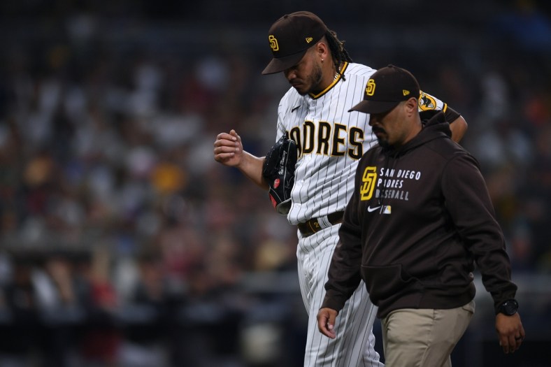 Jun 26, 2021; San Diego, California, USA; San Diego Padres starting pitcher Dinelson Lamet (left) walks to the dugout accompanied by a trainer during the third inning against the Arizona Diamondbacks at Petco Park. Mandatory Credit: Orlando Ramirez-USA TODAY Sports
