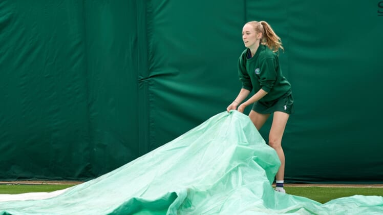 Jun 28, 2021; London, United Kingdom;  A young court coverer seen at work at the rain affected start to the Championships at All England Lawn Tennis and Croquet Club. Mandatory Credit: Peter van den Berg-USA TODAY Sports